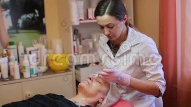 在美容院接受面部按摩的女人。 女人接受美容治疗，特写。 美容师的双手工作